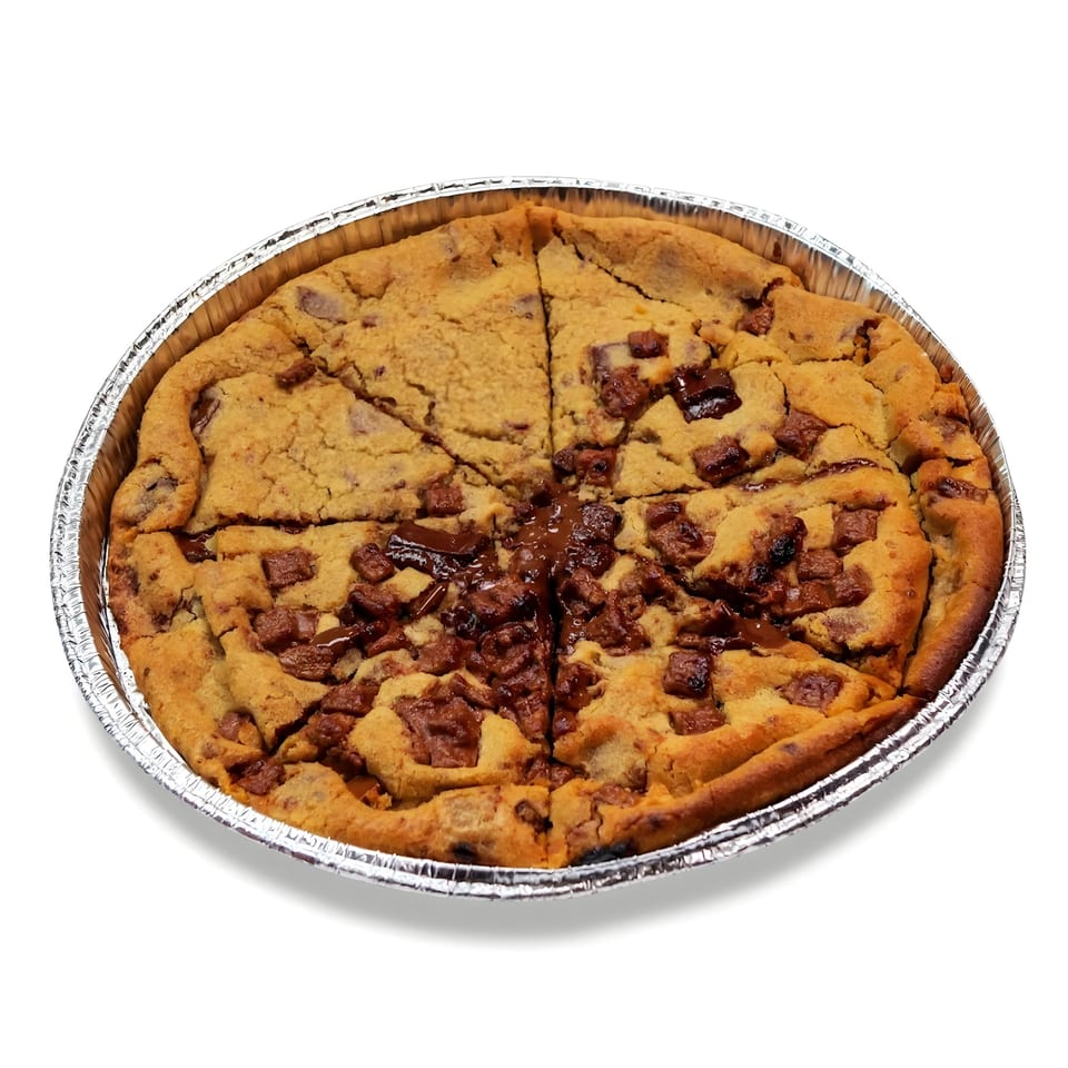 A large chocolate chip cookie pizza, sliced into wedges, in a foil pan.