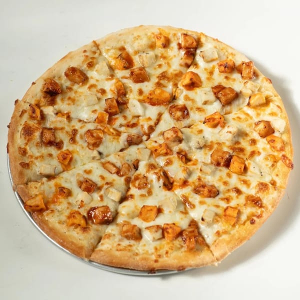 A whole Pizza Bites pizza with chicken and cheese on a metal tray.