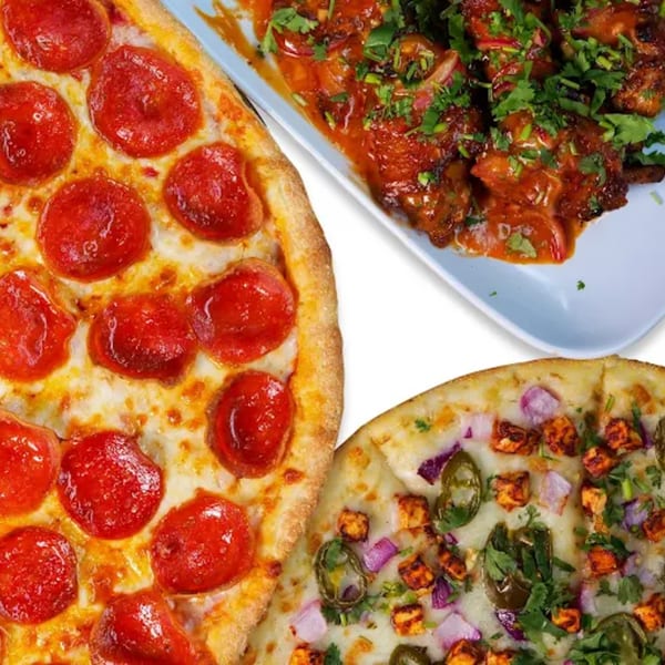 A pepperoni pizza, a paneer and jalapeño pizza, and a dish of chicken wings with sauce and cilantro.